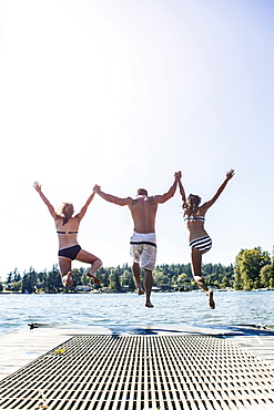 Young people jumping to lake from jetty, USA, Washington, Bellingham 