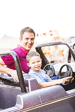 Father with son (4-5) driving toy car in amusement park, USA, Utah, Salt Lake City 