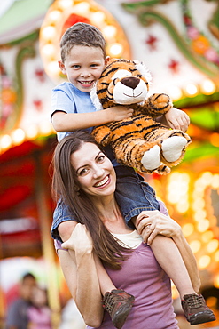 Mother giving her son (4-5) piggyback ride in amusement park, USA, Utah, Salt Lake City 