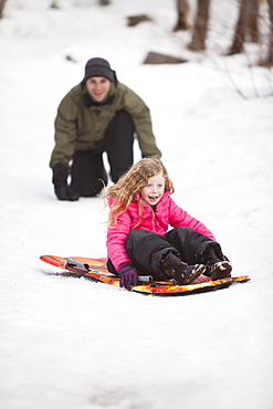 Young man sledding with girl (4-5)