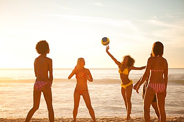 Young women playing with a beach ball in front of the sea