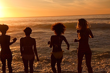 Four young women standing upright on the beach