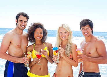 Four friends smiling while holding cocktails