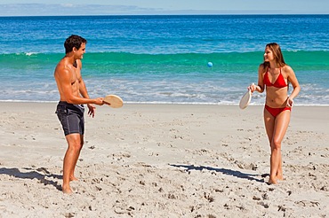 Tanned couple playing with beach racket