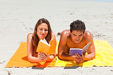 Tanned couple reading a book