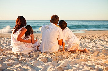 Back view of family enjoying the sunset on the beach