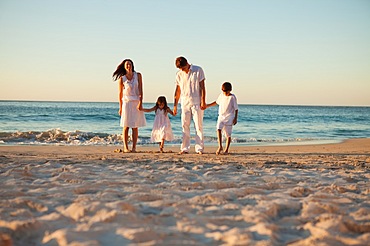 Family walking on the beach while holding hands