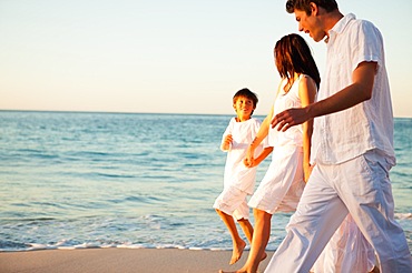 Family walking hand in hand at sunset time