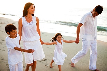 Cute family walking hand in hand at sunset time