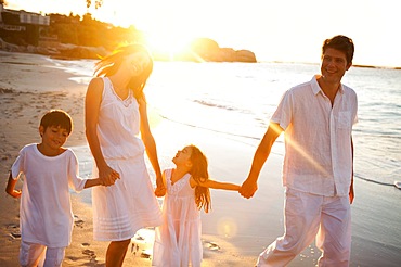 Family walking on the beach while the sun sets