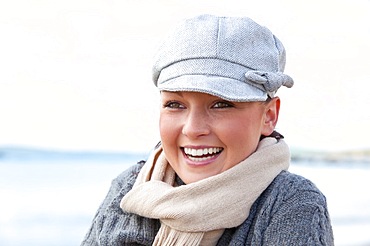 Pretty woman with scarf and hat standing on the beach