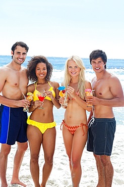 Four friends standing together while holding cocktails