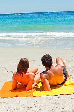 Tanned young lovers lying on the beach