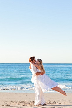 Man spinning his girlfriend at the beach