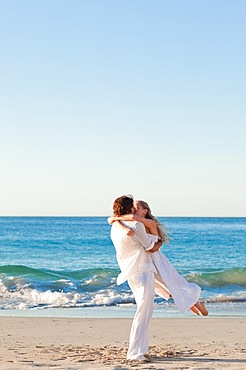 Man turning his girlfriend on the beach