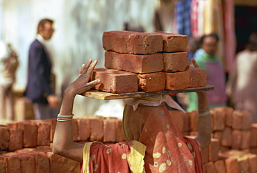 Woman construction worker carrying bricks on her head, Delhi, India, Asia