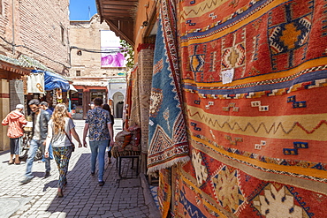 Tourists and locals walking alongside traditional rugs in the Medina's souks, Marrakech, Morocco, North Africa, Africa 