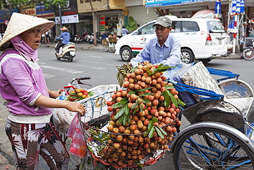 A cycle rickshaw driver stops to buy fruit from a lady outside Ben Thanh Market, Ho Chi Minh, Vietnam, Indochina, Southeast Asia, Asia