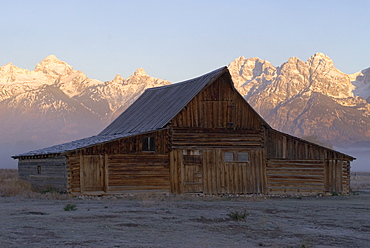 Traditional agricultural barn and the Teton Mountain range at dawn, Wyoming, USA