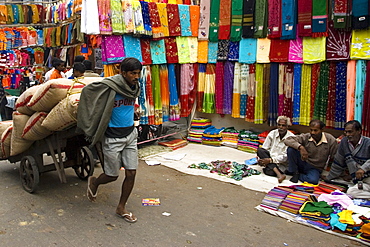 Man pulling cotton sacks on cart in Chandni Chowk shopping district of New Delhi, India