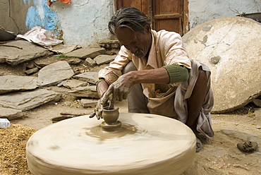 Potter creating clay pots on a manual stone wheel, Udaipur, Rajasthan, India