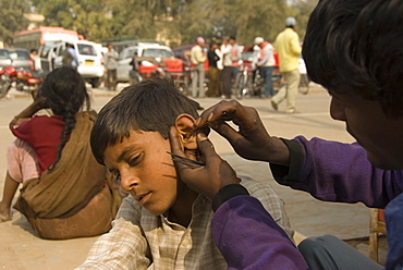 Young boy receiving treatment for an infected ear on the side of the street, Jaipur, Rajasthan, India