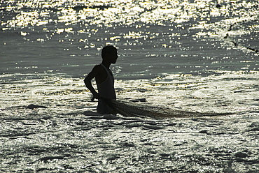 Fisherman standing in the sea ready to pull in the net, Goa, India