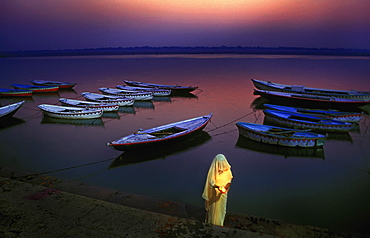 Devotee woman praying at the ghat ( river bank ) at dawn. Varanasi , India