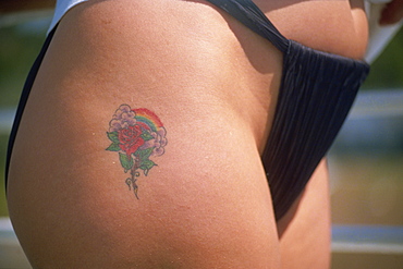 Rose and rainbow tattoo on thigh