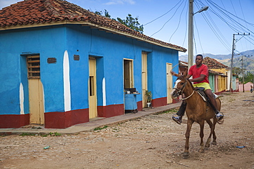 Man riding horse along cobbled street in historical center, Trinidad, Sancti Spiritus Province, Cuba, West Indies, Caribbean, Central America