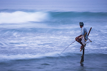 Stilt fishing, a stilt fisherman in the waves at Midigama near Weligama, South Coast, Sri Lanka, Indian Ocean, Asia 