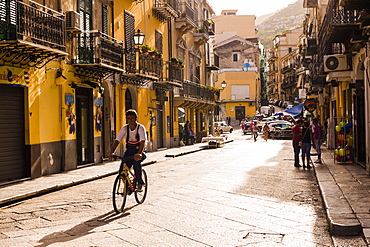 Sicilian man cycling along the main street at sunset, Monreale, near Palermo, Sicily, Italy, Europe