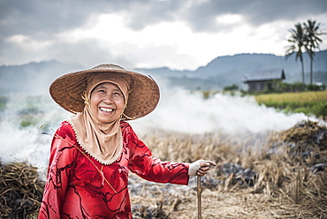 Portrait of a farmer burning crops in rice paddy fields, Bukittinggi, West Sumatra, Indonesia, Southeast Asia, Asia