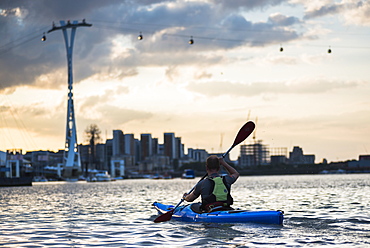 Kayaking at sunset under the Emirates Air Line Cable Car across the River Thames, Greenwich, London, England, United Kingdom, Europe