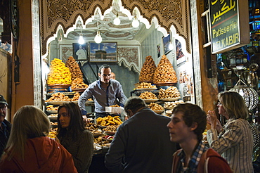 Shop keeper selling sweet cakes to tourists in the souks at night, Marrakech (Marrakesh, Morocco, North Africa, Africa