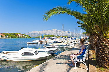 Tourist sitting in Lumbarda Harbor, Korcula Island, Dalmatian Coast, Adriatic, Croatia, Europe