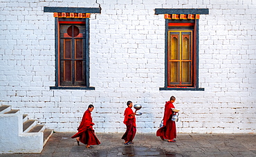 Three Buddhist monks carrying food bowls, Kyichu Temple, Bhutan, Asia