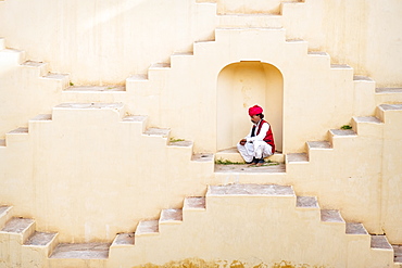 Man in Indian traditional clothing sitting in alcove on Panna Meena Ka Kund in Jaipur, India, Asia