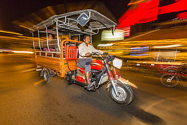 Night photograph of tuk-tuk and driver in the capital city of Phnom Penh, Cambodia, Indochina, Southeast Asia, Asia