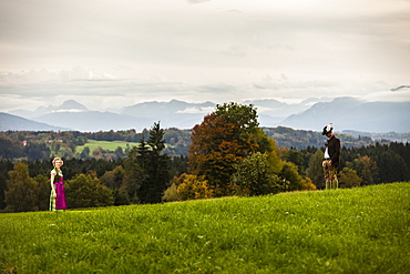 Couple wearing traditional Bavarian costumes standing on a meadow, Bad Toelz, Upper Bavaria, Germany