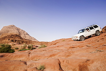 Off-road vehicle downhill driving above a slab of rock, Wadi Rum, Jordan, Middle East