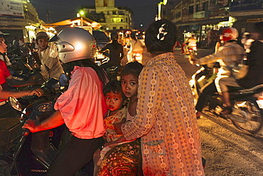 Two women with two children sitting on one motorscooter in the center of Battambang, Cambodia, Southeast Asia