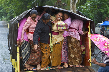 Balinese women squeezing themself on the back of a truck on the way home from a temple visit, Pura Luhur Batu Karu, Bali, Indonesia