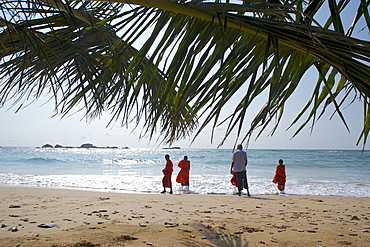 View through palm leaves towards the beach, buddhist novices at the sea, Hikkaduwa, Southwest coast, Sri Lanka