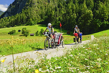 Two cyclists with child trailer riding along Inn cycle route, Zams, Tyrol, Austria