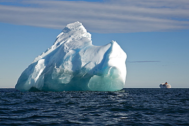 Iceberg in bright sunlight with expedition cruise ship MS Hanseatic (Hapag-Lloyd Cruises) in the background, Bird Point, Ross Is