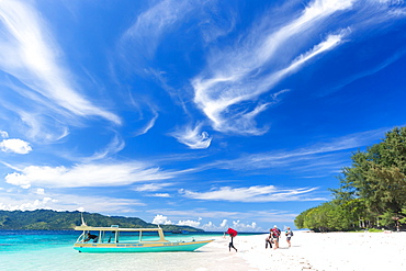 Tourists near a boat at white sandy beach, Gili Meno, Lombok, Indonesia