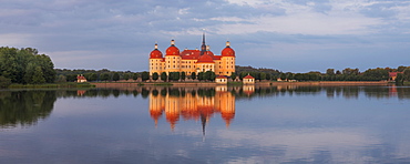 Panorama of the baroque Moritzburg castle in the evening sun with its reflection in the castle pond, near Dresden, Saxony, Germany