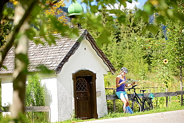 Young female cyclist having a break and reading a map, Tannheimer Tal, Tyrol, Austria