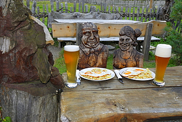 Carved couple at a table with food and wheat beer, alpine lodge Sulzenau, Stubaier Alps, Stubai, Tyrol, Austria